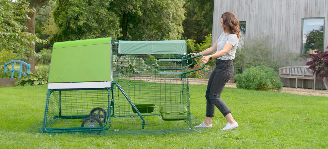 En kvinna flyttar en Eglu Go upp hönsgård